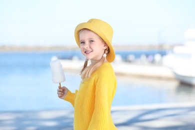 Photo of Cute little girl with cotton candy outdoors