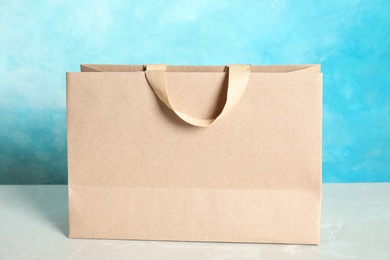 Photo of Paper shopping bag on table against color background. Mock up for design