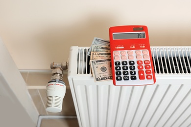 Calculator and money on heating radiator indoors