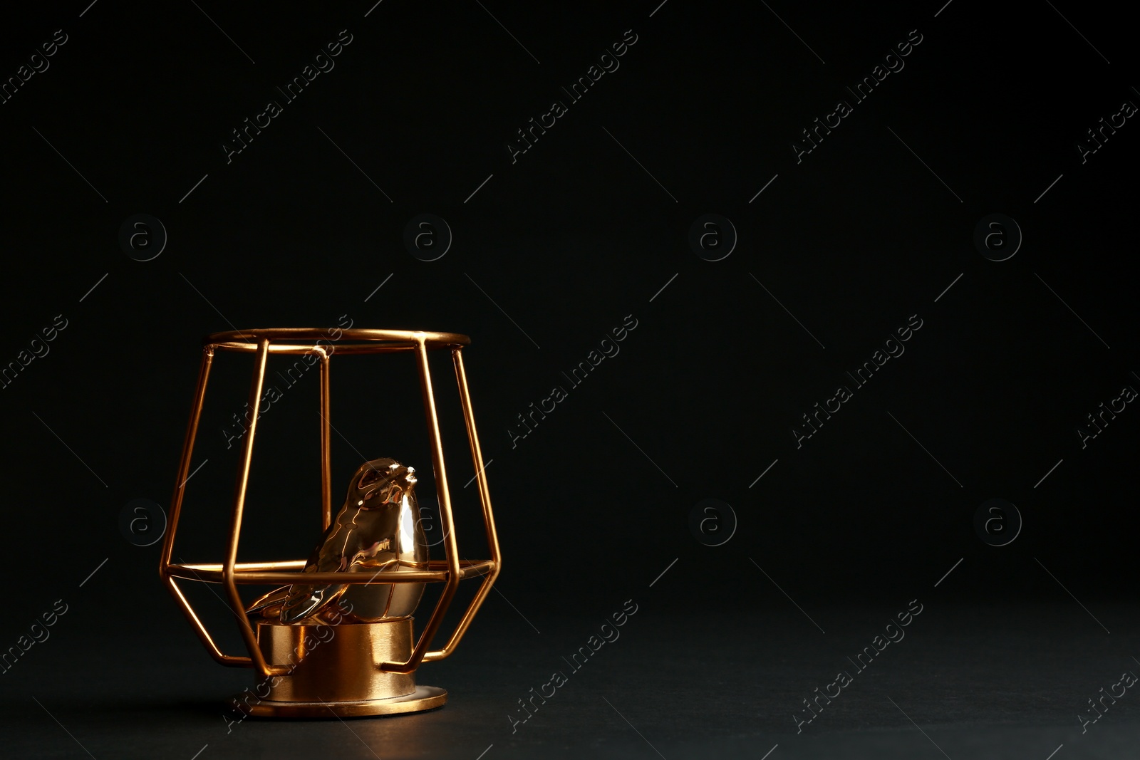 Photo of Composition with decorative gold bird on black background. Space for text