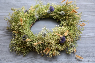 Photo of Beautiful wreath made of wildflowers on grey wooden background, closeup