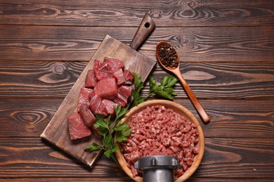 Photo of Manual meat grinder with beef mince, peppercorns and parsley on wooden table, flat lay