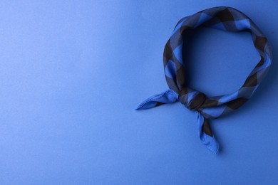 Photo of Tied bandana with check pattern on blue background, top view. Space for text