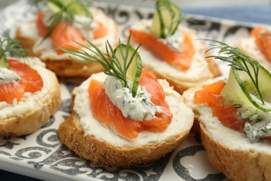 Tasty canapes with salmon, cucumber, cream cheese and dill on table, closeup