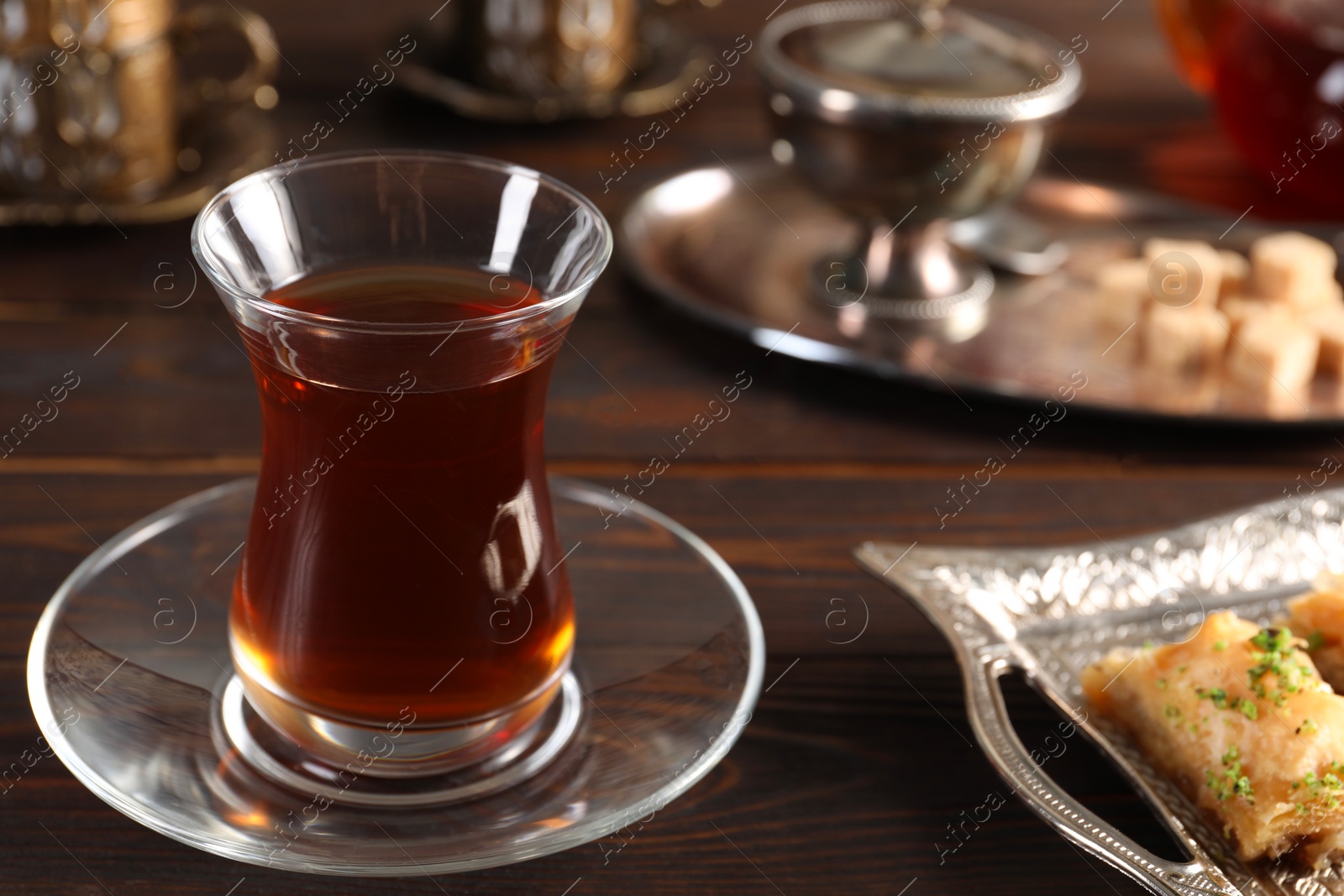 Photo of Traditional Turkish tea in glass and baklava on wooden table, closeup