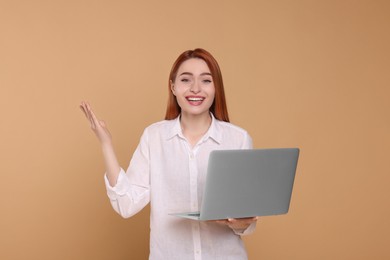 Happy young woman with laptop on beige background