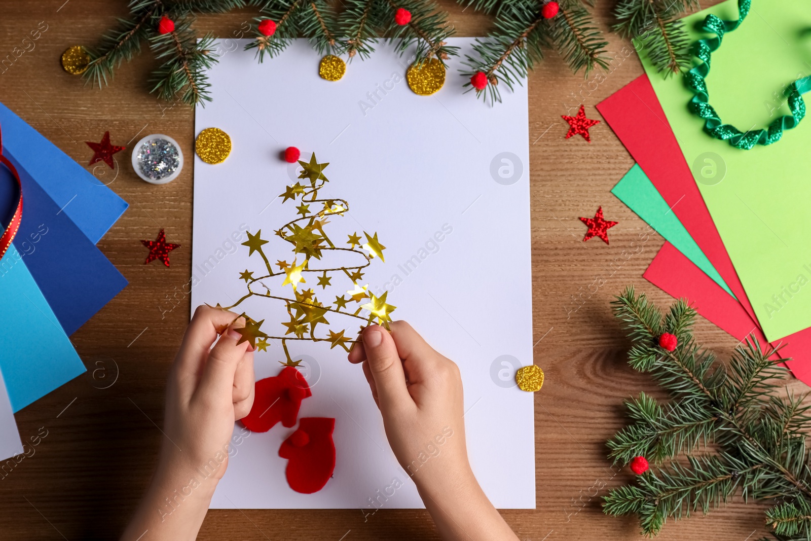 Photo of Little child making Christmas card on wooden table, top view