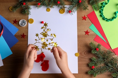 Little child making Christmas card on wooden table, top view