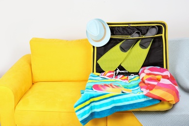 Photo of Packed suitcase for summer vacation on sofa in living room