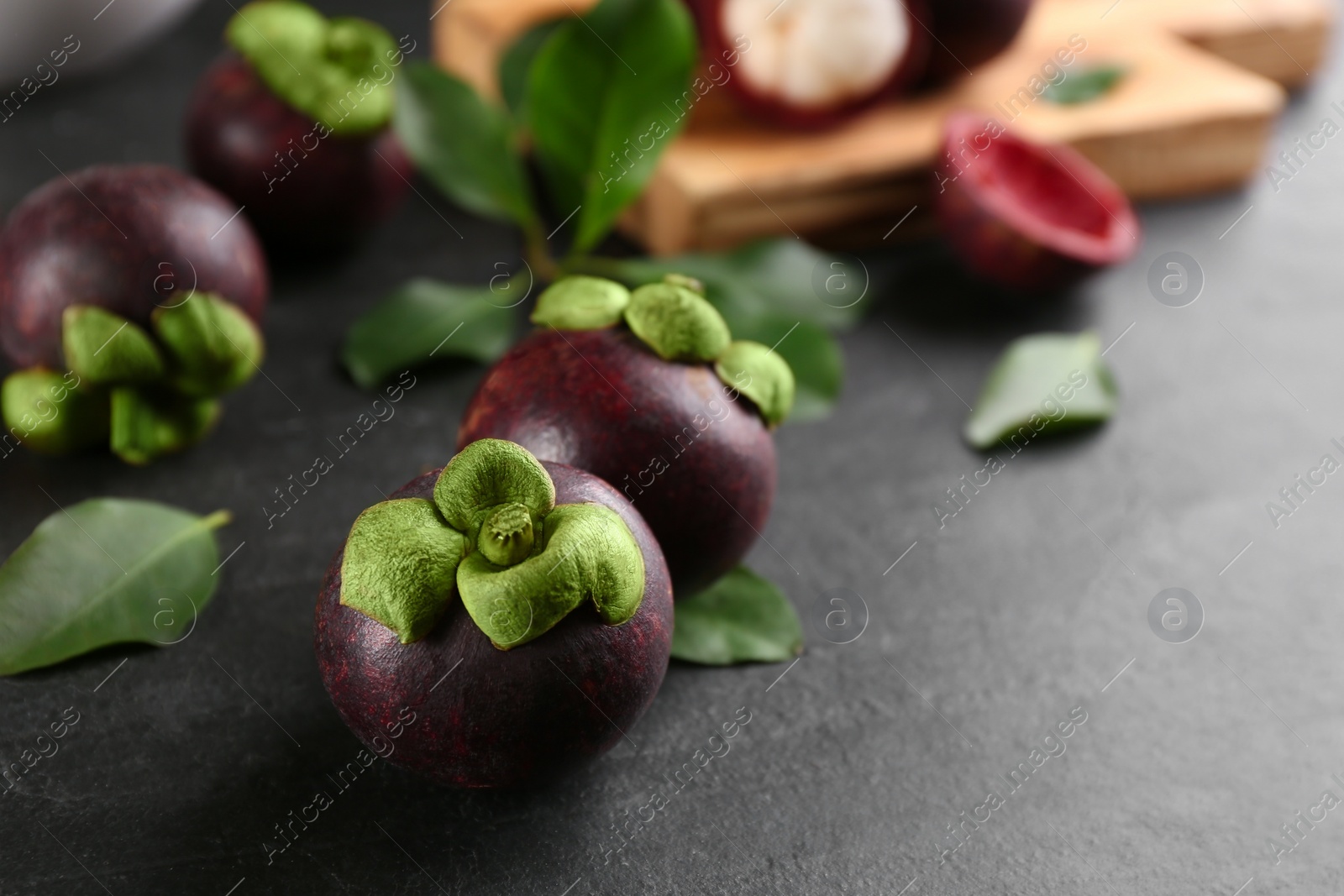 Photo of Fresh ripe mangosteen fruits on dark grey table