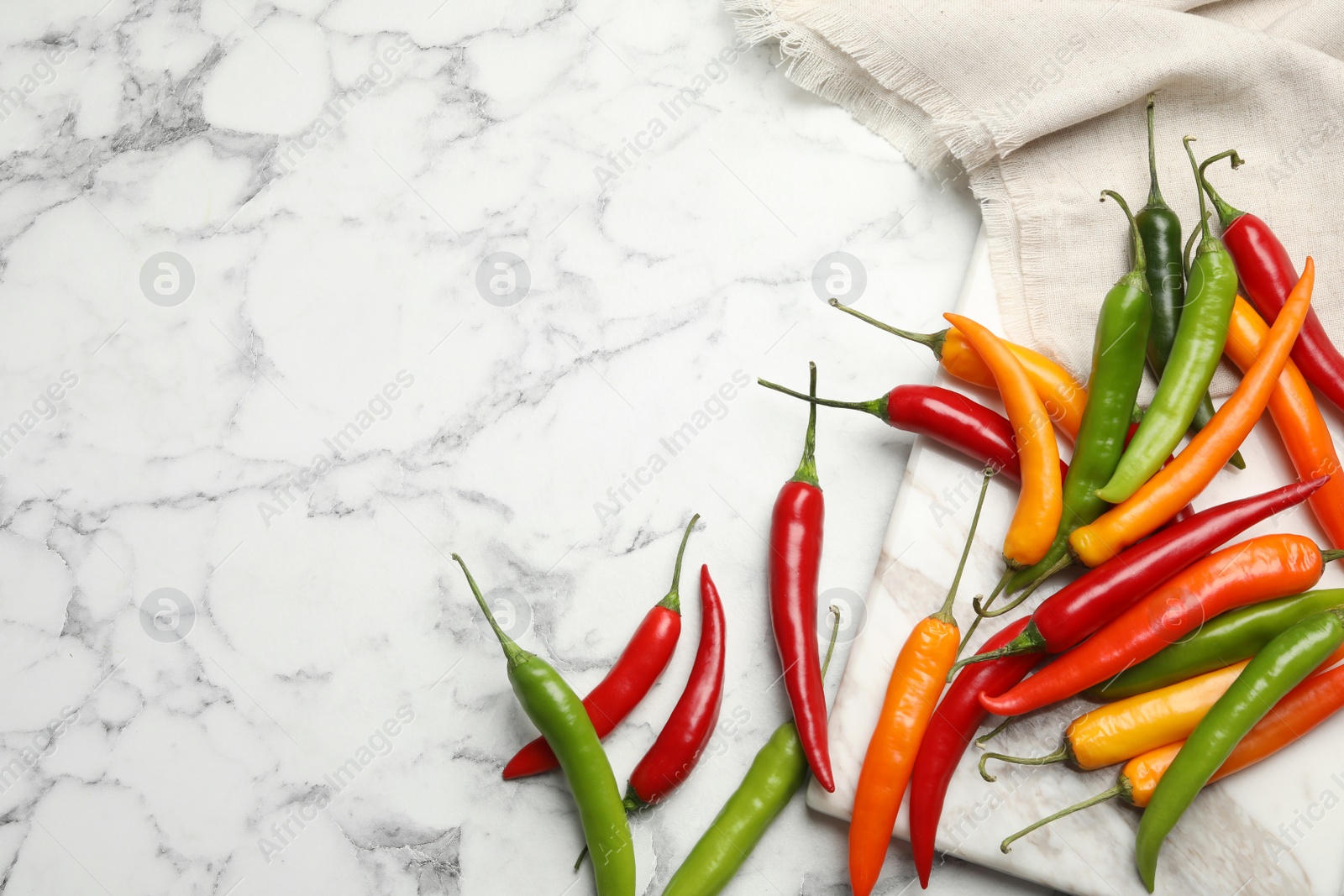 Photo of Different chili peppers on marble table, flat lay. Space for text