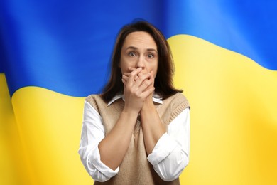 Image of Mature woman feeling fear and national flag on background. Stop war in Ukraine