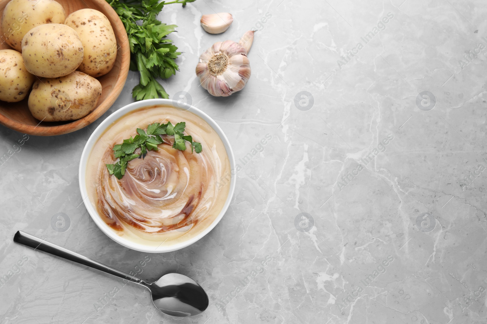 Photo of Delicious cream soup with soy sauce and parsley served on light grey marble table, flat lay. Space for text