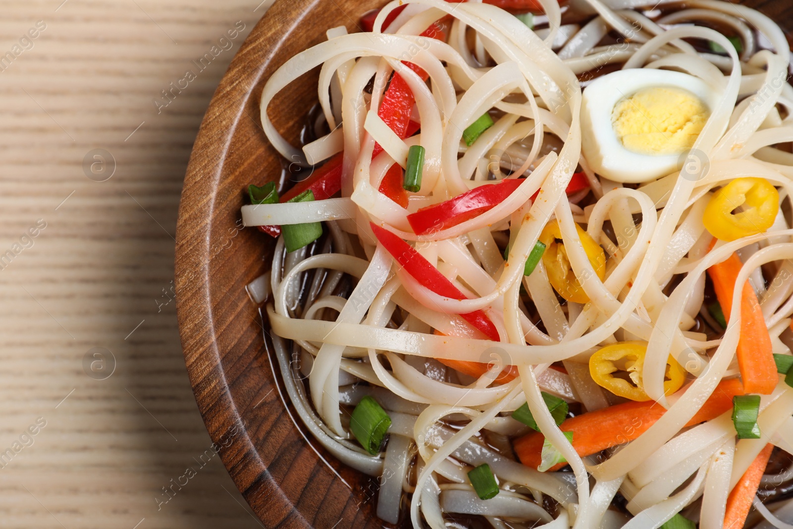 Photo of Bowl of noodles with vegetables and egg on table, closeup