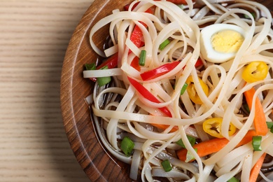 Photo of Bowl of noodles with vegetables and egg on table, closeup