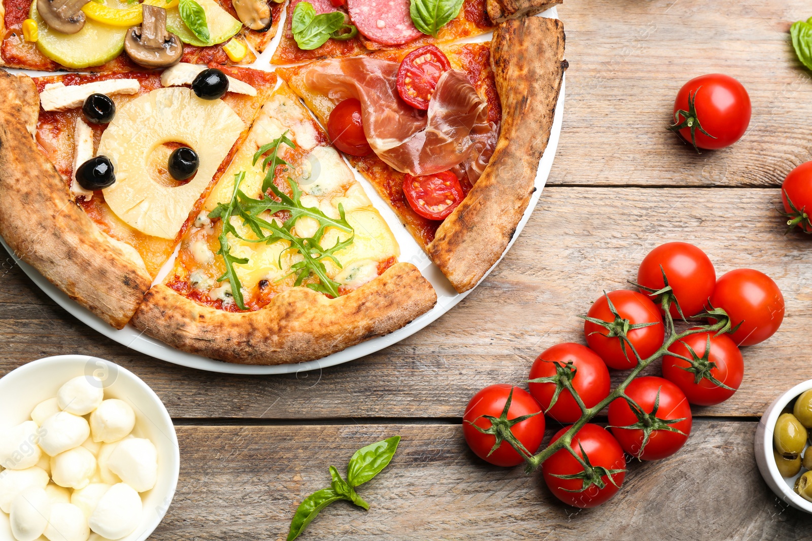 Photo of Slices of different pizzas on wooden table, flat lay