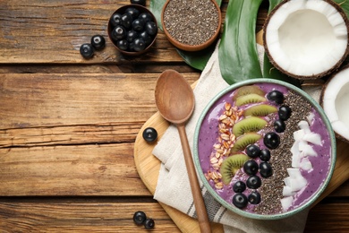 Delicious acai smoothie and fruits in bowl served on wooden table, flat lay. Space for text