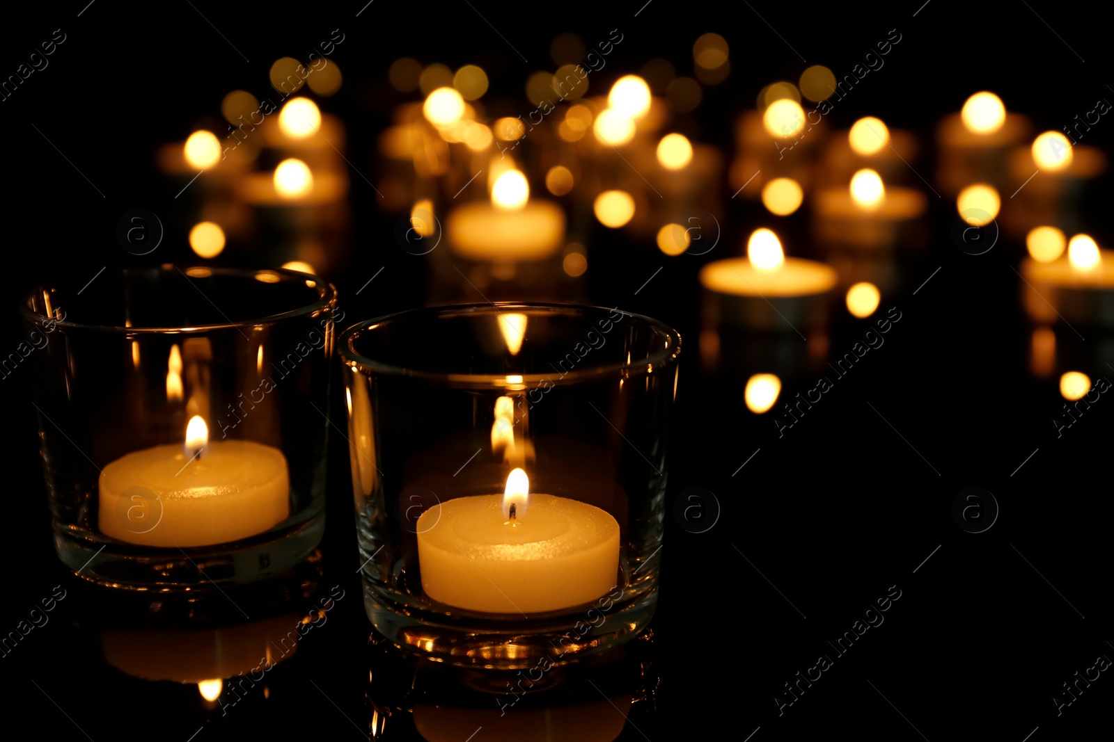 Photo of Burning candles in glass holders on table