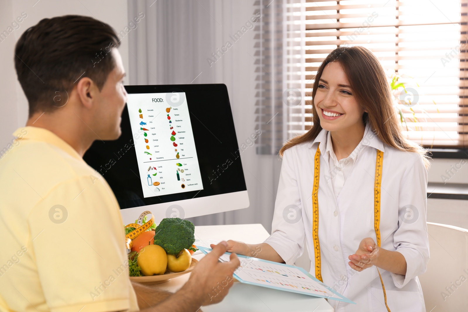 Photo of Young nutritionist consulting patient at table in clinic