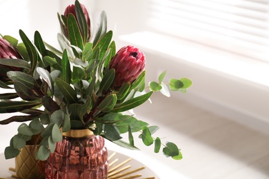 Vase with bouquet of beautiful Protea flowers on table indoors
