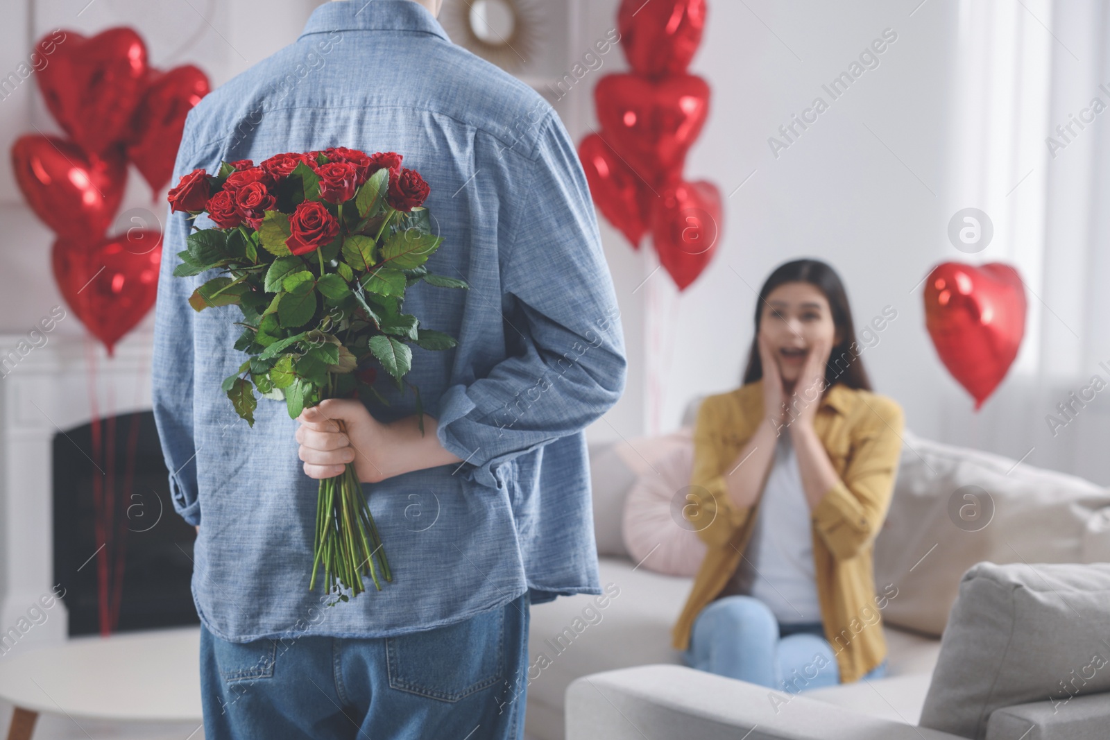 Photo of Man hiding bouquet of red roses for his beloved woman, closeup. Valentine's day celebration