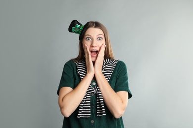 Emotional woman in St Patrick's Day outfit on light grey background