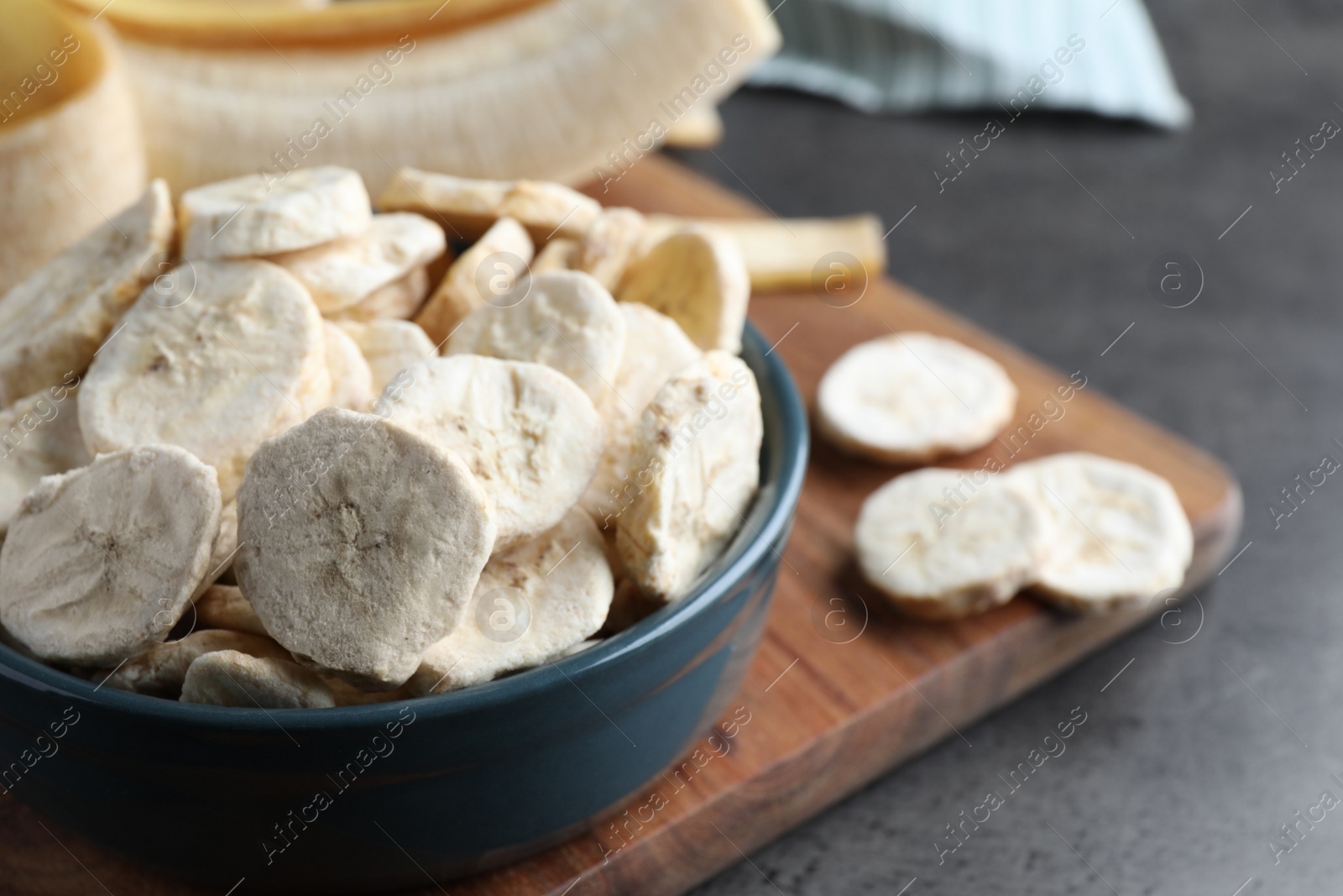 Photo of Freeze dried and fresh bananas on grey table, closeup. Space for text