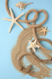 Photo of Beautiful starfishes, sea shell, rope and sand on light blue background, flat lay