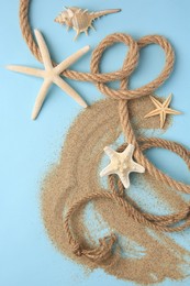 Beautiful starfishes, sea shell, rope and sand on light blue background, flat lay