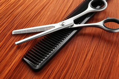 Photo of Thinning scissors and comb on red hair. Hairdresser service