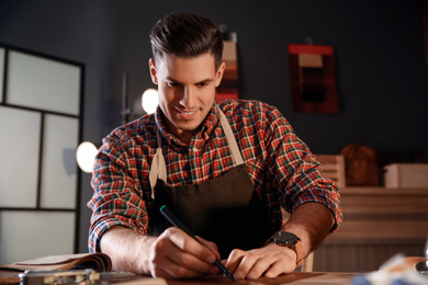 Photo of Man working with piece of leather in workshop