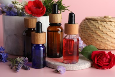 Aromatherapy. Different essential oils and flowers on pink background