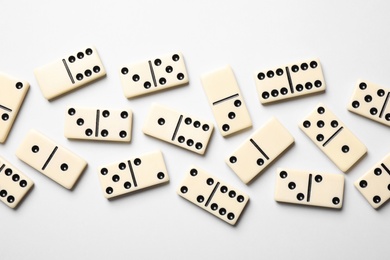 Photo of Classic domino tiles on white background, flat lay