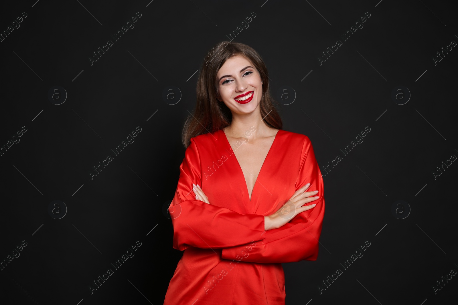 Photo of Happy woman in red dress on black background. Christmas party