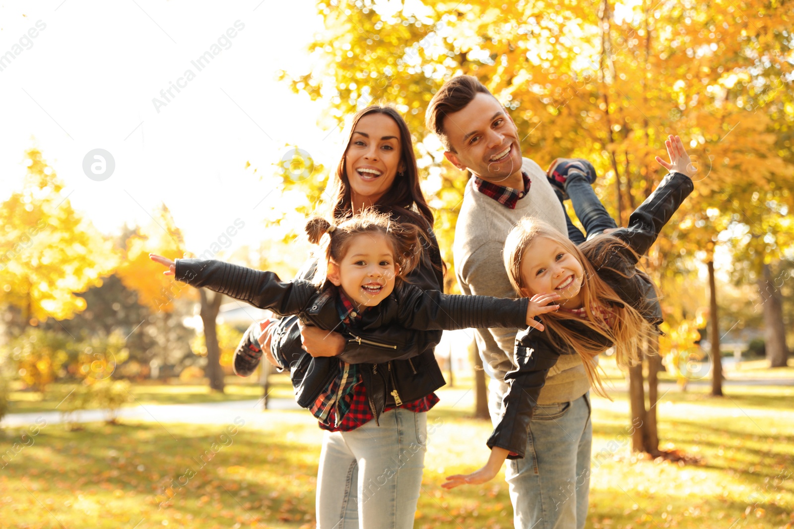 Photo of Happy family with little children in sunny park. Autumn walk