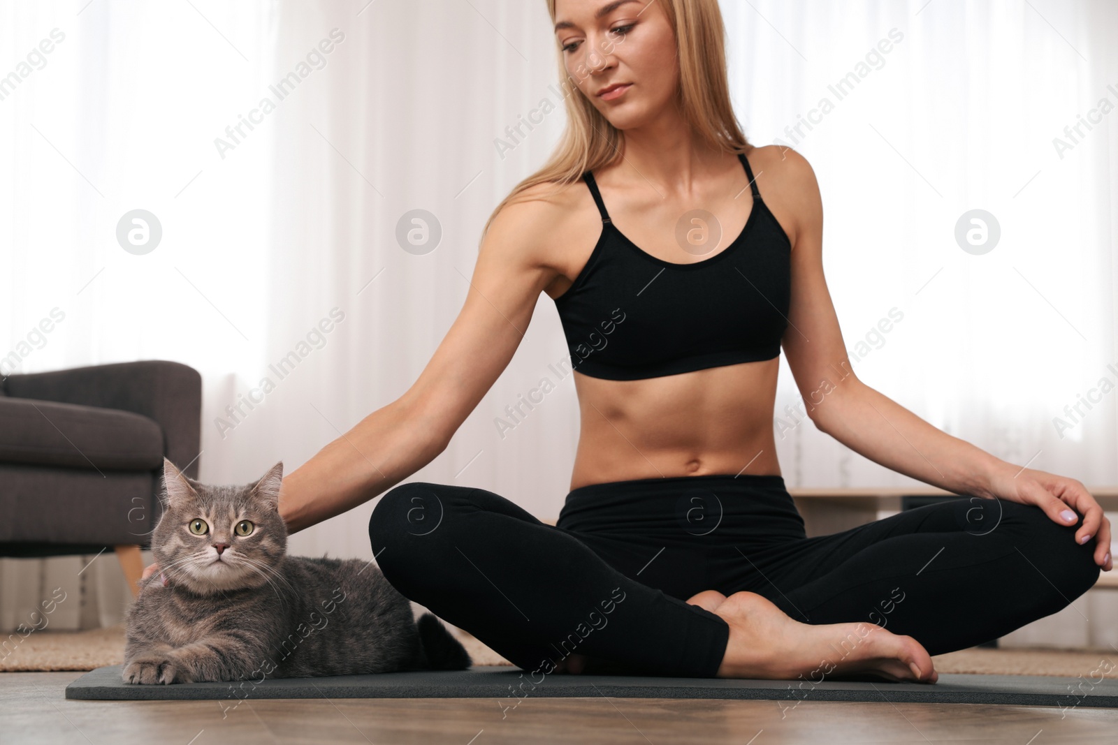 Photo of Woman stroking her cat while practicing yoga at home