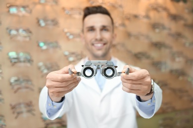 Male ophthalmologist with phoropter in optical store