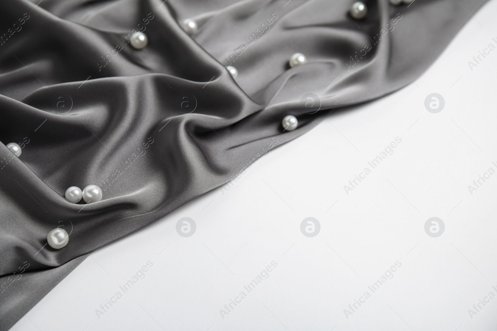 Photo of Texture of delicate black silk with pearls on white background