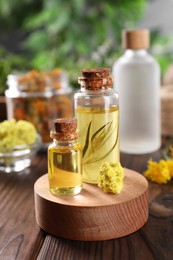 Photo of Bottles of essential oils and dry herbs on wooden table