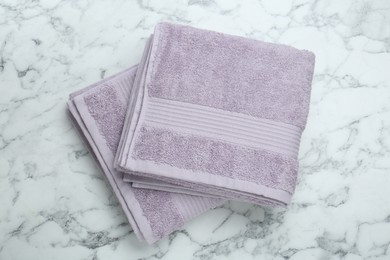 Photo of Violet terry towels on white marble table, top view