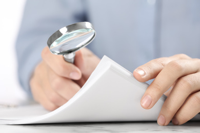 Photo of Woman using magnifying glass at table, closeup