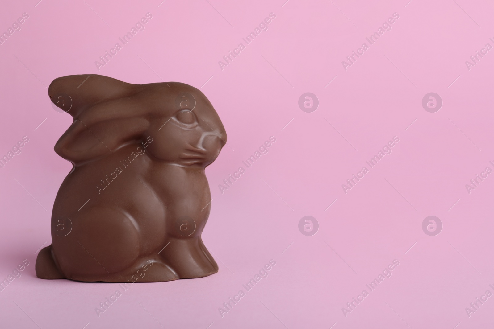 Photo of Chocolate bunny on pink background, space for text. Easter celebration