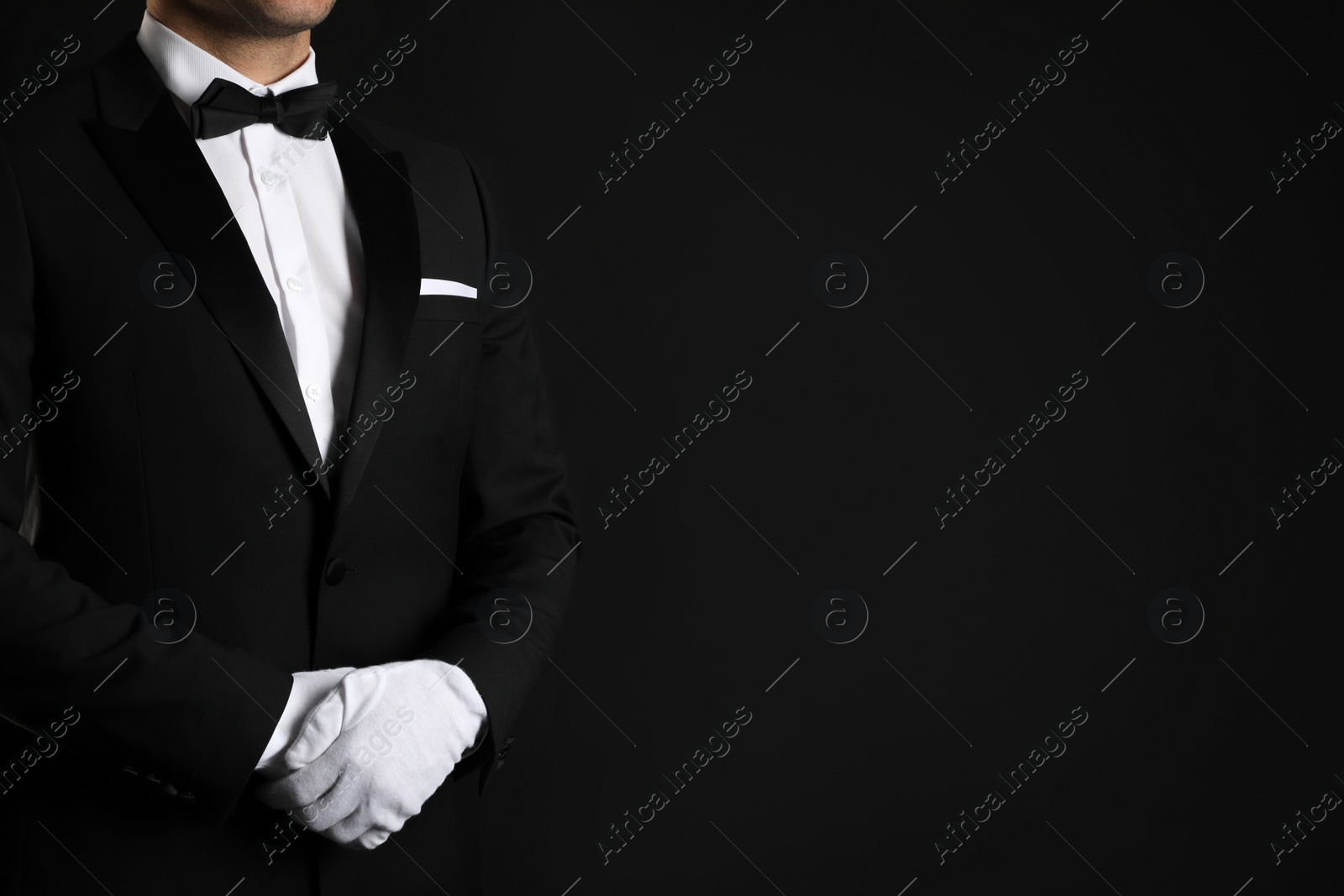 Photo of Butler in elegant uniform on black background, closeup. Space for text