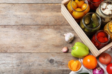 Photo of Jars with pickled vegetables on wooden table, flat lay. Space for text