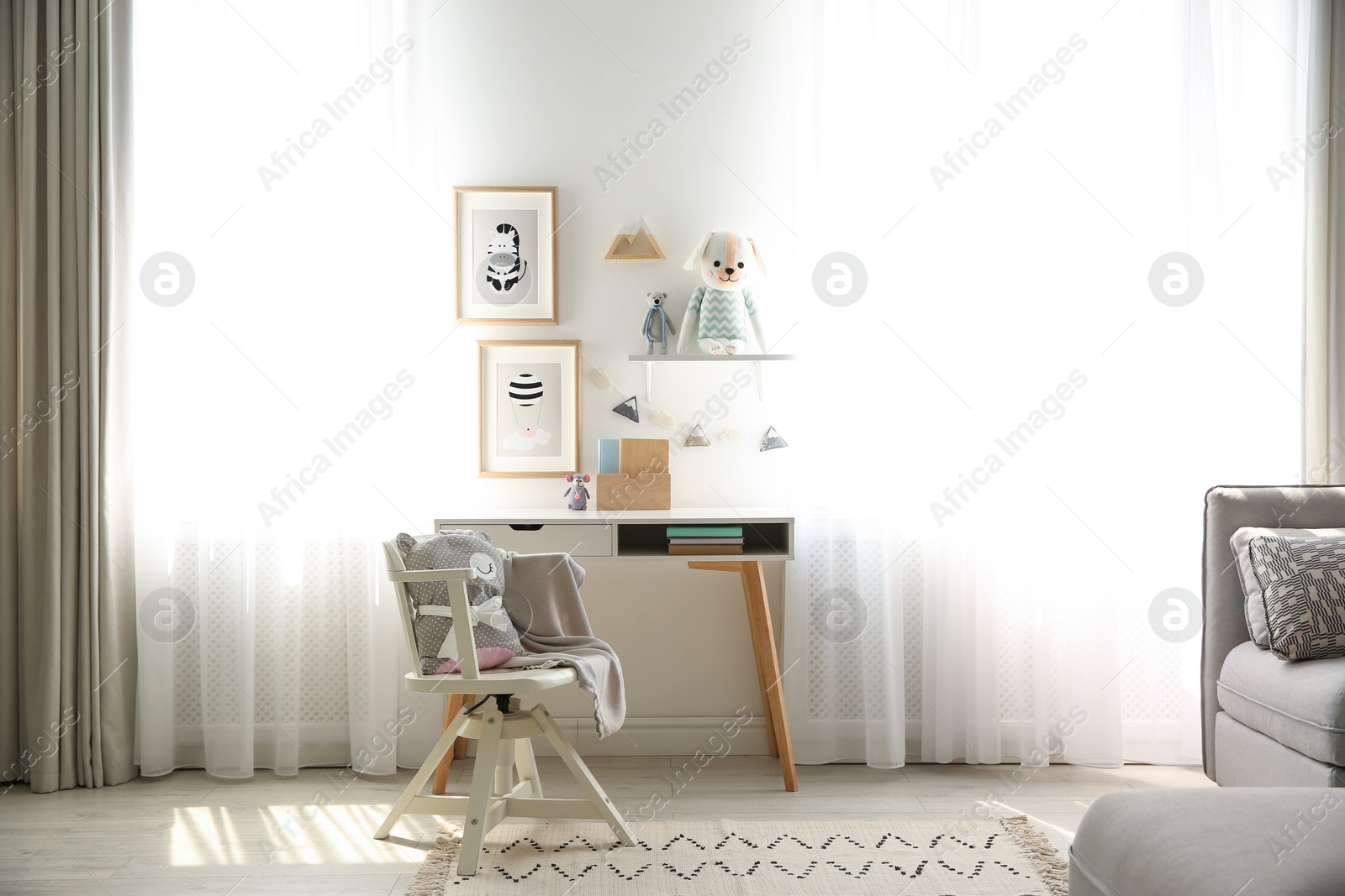 Photo of Stylish child's room interior with desk and beautiful pictures