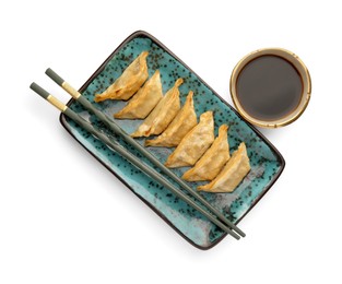 Photo of Delicious gyoza (asian dumplings), soy sauce and chopsticks isolated on white, top view