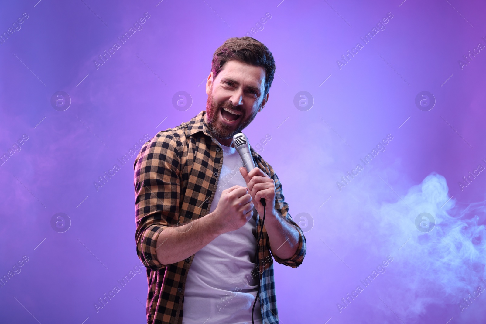 Photo of Handsome man with microphone singing in neon lights