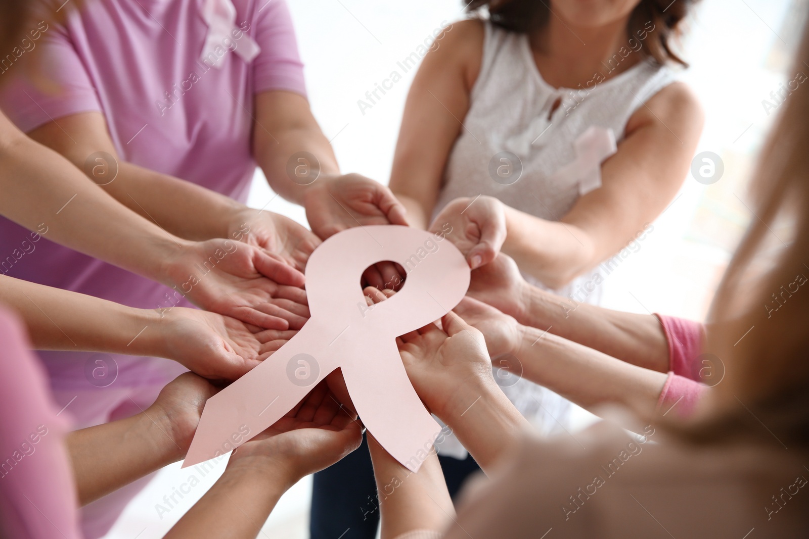 Photo of Women holding pink paper ribbon, closeup. Breast cancer awareness concept