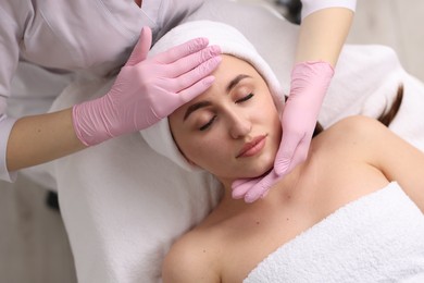 Cosmetologist making face massage to client, top view