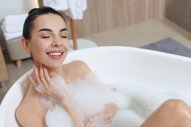 Photo of Woman taking bath with shower gel indoors